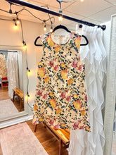 Load image into Gallery viewer, Floral dress hanging with pockets. Denim feel and ecru color with pink, yellow, green flowers. 