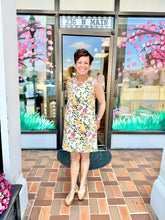 Load image into Gallery viewer, Woman in a floral dress standing in front of a store with cherry blossom decorations.